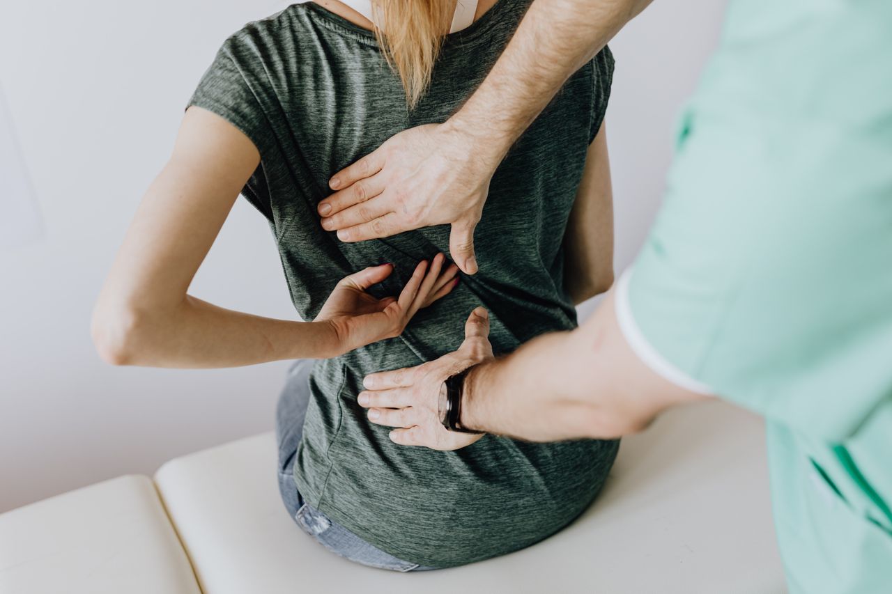 Mastering the First Impression: Your intriguing post title goes here From above of crop faceless slim female patient sitting on examination couch and indicating osteopath in uniform pain spot on back in clinic